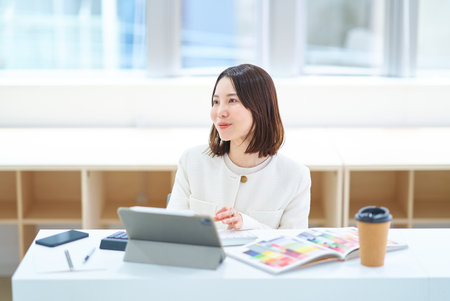 A young woman in a suit working indoorsの写真素材