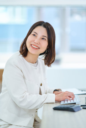 A young woman talking to a colleague at workの写真素材