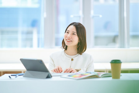 A young woman in a suit working indoorsの写真素材
