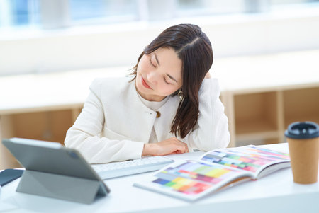 A woman looking tired while working on a computerの写真素材