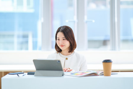 A young woman in a suit working indoorsの写真素材
