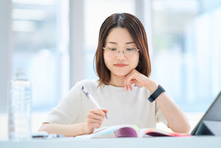 A young woman studying with textbookの写真素材