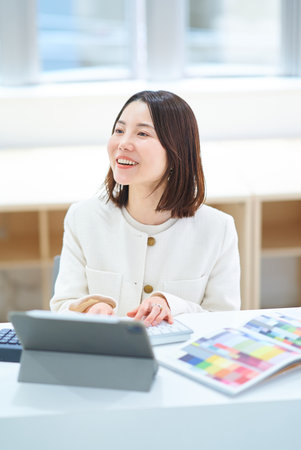A young woman in a suit working indoorsの写真素材