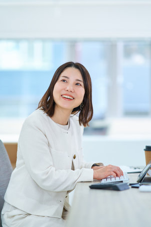 A young woman talking to a colleague at workの写真素材