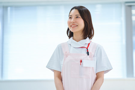 A woman in a white coat and apron in a roomの写真素材