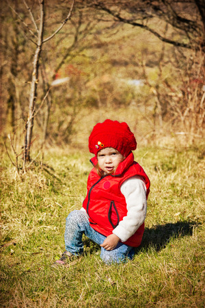 Expressive little girl in the grass on a vintage backgroundの写真素材