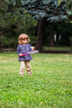 Cute little girl, learning to play badminton in the parkの写真素材