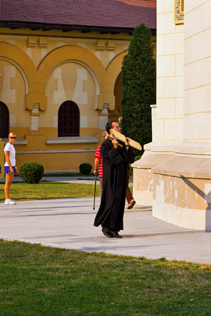 Alba Iulia, Romania - August 26, 2012: Orthodox priest hitting a wooden board calling the people to prayer and serviceのeditorial素材