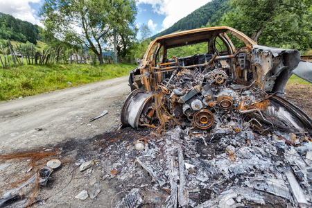 Vehicle burned to the metal near a country roadの写真素材