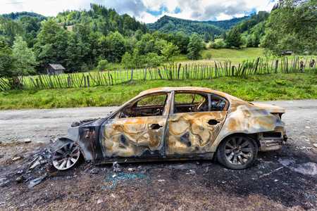 Vehicle burned to the metal near a country roadの写真素材