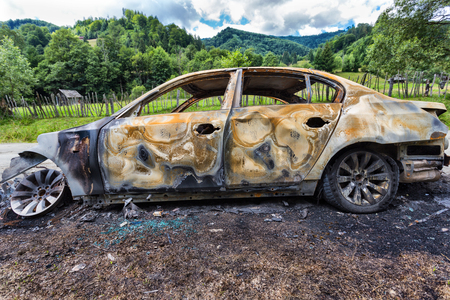 Vehicle burned to the metal near a country roadの写真素材