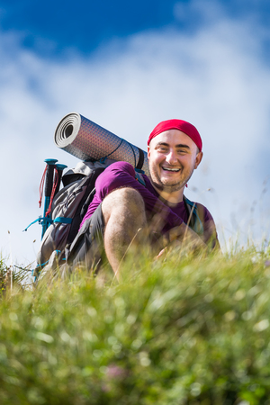 Hiker smiling while sitting down on the mountain trail for restの写真素材
