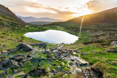  Dawn on a mountain lake in the mountains, the Ukrainian Carpathians, Lake Vorozheska, green slopes, sunbeams, a blue lake high in the mountainsの写真素材