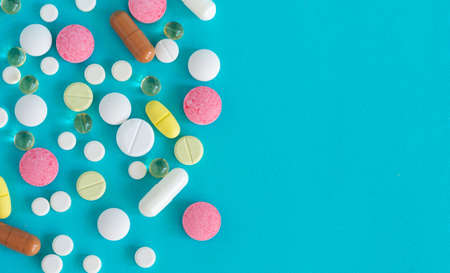 Many pills are poured from a medicine bottle. Pills and pills on a blue background. Medical tablets:...