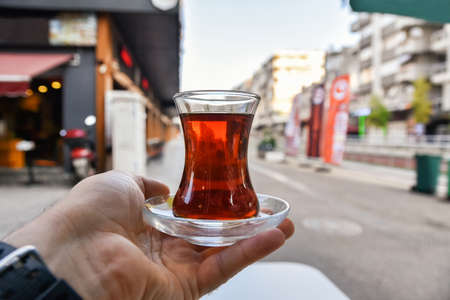 Cup of Turkish tea in hand. Streets of morning Antalya, black tea.の写真素材