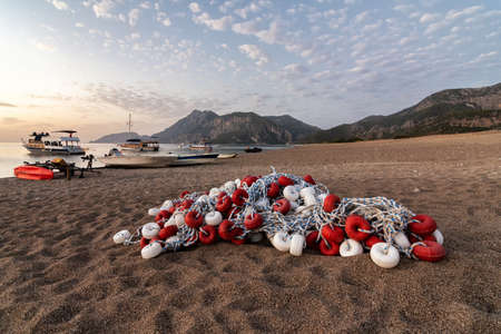 Morning on the beach in the village of Cirali, fishing nets lie on the yellow sand. Boats and ships...