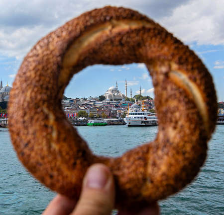 Traditional Turkish pastries - Simit in hand. View of the old city of Istanbul and the largest mosque.の写真素材