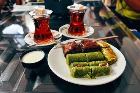 Sweet baklava on plate with tea on table