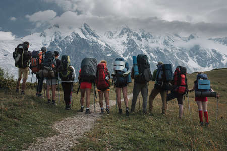 A group of tourists with backpacks admire the view of the main ridge of the Caucasus, Svaneti, Georgiaの写真素材