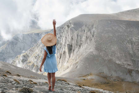 A happy female tourist in blue dress walks along the path to the top of the famous mythological Mount Olympus. Natural parks and attractions of Greeceの写真素材