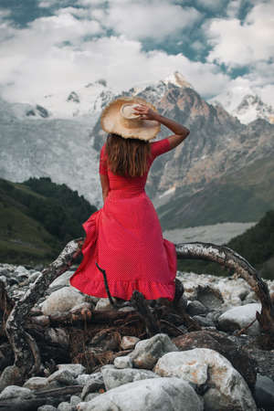 Young beautiful girl in the red dress with on the background of the Adishi glacier. Adish Glacier in Svaneti and the Caucasus Mountains.の写真素材