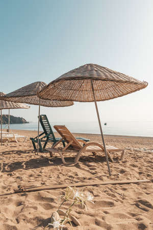 Sunbeds and rattan parasols on sandy seaside.の写真素材