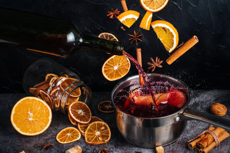 Falling mulled wine ingredients, citrus fruits, cinnamon and star anise fly from a height and create splashes. A cauldron of mulled wine into which fruit and spices are falling and wine pouring. In the dark background are dried citrus fruitsの写真素材
