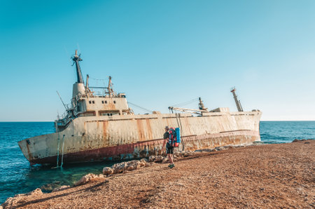 A ghost ship on a beach in Cyprus near Paphos. A tourist with a backpack walks along the beach.の写真素材