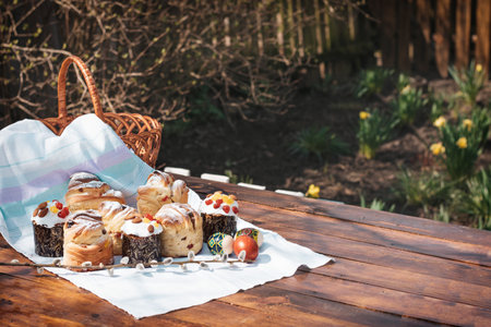 Easter baking on a wooden table in a spring garden. A lot of pastries on the table next to a basket for going to church.の写真素材