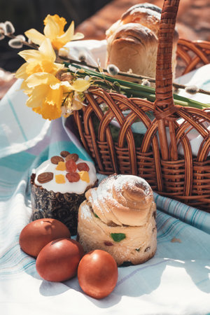 Easter baking on a wooden table in a spring garden. A lot of pastries on the table next to a basket for going to church.の写真素材