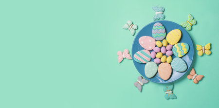 Easter banner on a mint background. Homemade gingerbread cookies on a blue plate, Easter eggs and...