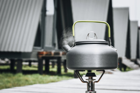 Cooking, heating a tourist kettle on a portable gas burner with a red gas cylinder. Cooking in a tourist campsite in the mountains. Summer outdoor activitiesの写真素材