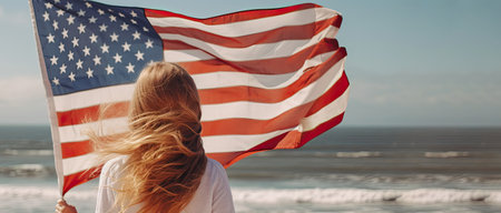American flag. patriotic girl with long red hair, holding an american flag waving in the wind on the ocean beach. National 4 july. Memorial day. Created with generative AI technologyの素材
