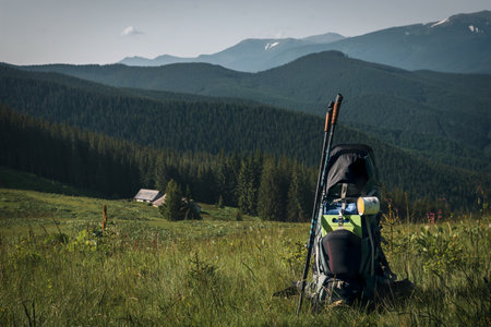 Backpack, trekking poles and sleeping mat in mountains, space for text. Tourism equipment