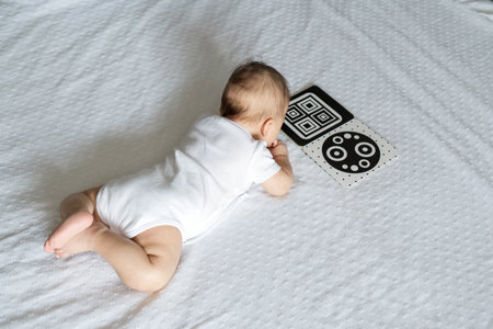 A baby looks at a black and white contrast educational book. Intellectual development of newborns....