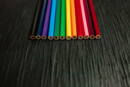 Many colored pencils on a black background. New pencils. Isolated background to insert text