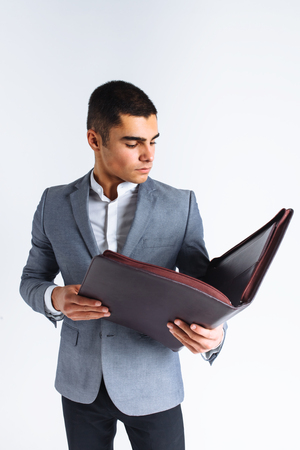Handsome man with folder man reading a menu, a stylish business guy in suit in Studio on white background isolatedの写真素材