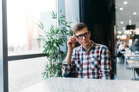 Portrait of a young man in glasses and a shirt with a positive mood and a wide smile, stylish manの写真素材