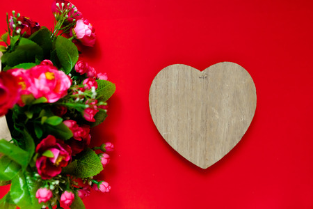 Valentine's day gift for the second half, a bouquet of flowers, a romantic photo, a wooden heart on a red background, background suitable for advertisement , insert text,loveの写真素材