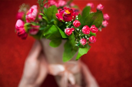 Valentine's day,florist woman packs a bouquet of flowers of roses in a paper wrapper with a bow on wooden table, suitable for advertisement, insert textの写真素材