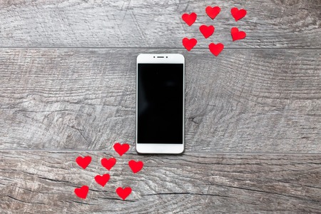 Valentine's day ,phone on wooden grey background,with red hearts,the love,the connection between the two,suitable for advertisement insert textの写真素材