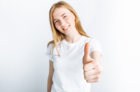 Beautiful young girl showing thumb in Studio, isolated background, super emotionの写真素材