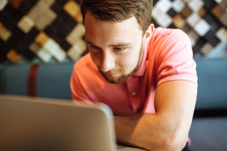 A young man sitting in a cafe with a laptop, working, shopping onlineの写真素材