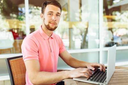 a young man sits in a cafe on the street, outdoors with a laptop, job searchの写真素材