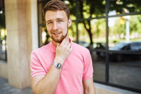 portrait of handsome young man with beard in town returning after school or work