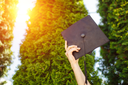 Successful graduate, in academic dresses, raised up graduation cap, farewell study, can be used for advertising,の写真素材