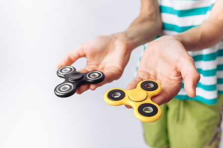 Portrait of a beautiful and emotional boy, holding spinners, plays, white background, blue t-shirt,の写真素材