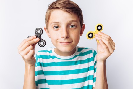Portrait of a beautiful and emotional boy, holding spinners, plays, white background, blue t-shirt,の写真素材