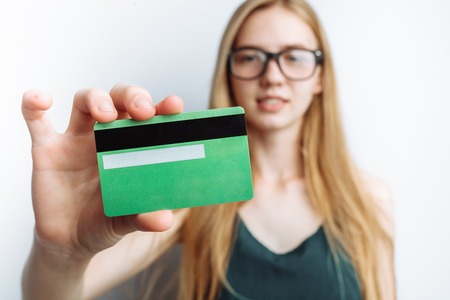 Beautiful girl shows Bank card, white background, advertising cardの写真素材