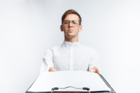 Portrait of a young guy in glasses, in a white shirt, shows an empty folder on the camera , isolated on a white background,の写真素材